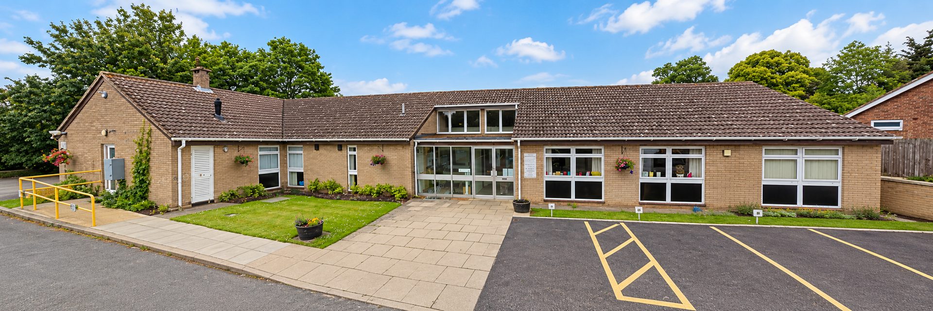 Litcham Health Centre: a single-storey brick building with a glass entrance, front lawn and car park